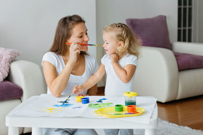 Mother and toddler daughter painting at home. happy creative family with child spending time