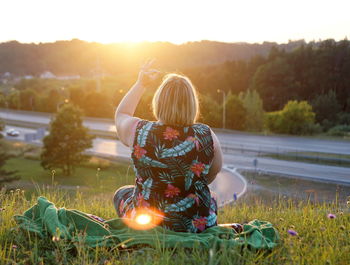 Rear view of woman sitting on field against clear sky