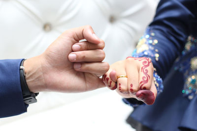 Cropped hand of groom holding bride finger