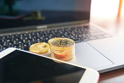 Close-up of coins and smart phone on laptop 