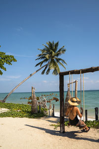 Rear view of woman sitting on swing at beach