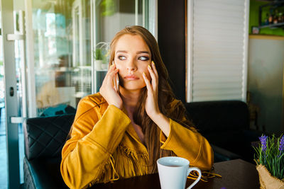 Portrait of young woman sitting on table at cafe