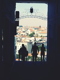 Rear view of silhouette people standing by buildings in city