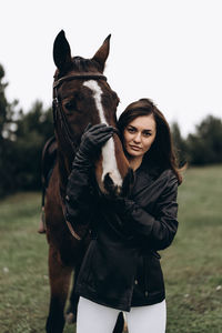 Portrait of young woman riding horse on field