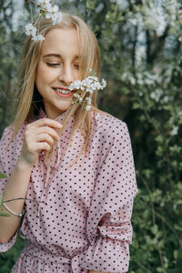 Blonde girl on a spring walk in the garden with cherry blossoms. female portrait, close-up. 