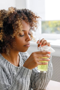 Portrait of young woman holding drink at home