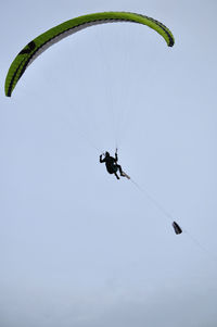 Low angle view of person paragliding against sky