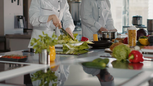Midsection of chefs preparing food in kitchen