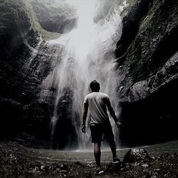 Rear view of man looking at waterfall