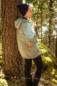 Female tourist leaning on tree in wood scenic photography