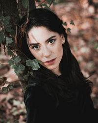 High angle portrait of beautiful woman leaning on tree trunk