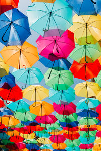 Low angle view of multi colored umbrellas hanging against sky