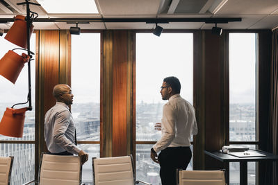 Male entrepreneurs discussing while standing in board room during meeting