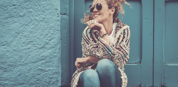 Young woman looking down while sitting against wall