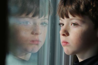 Close-up portrait of girl looking through window