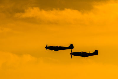 Low angle view of silhouette airplane against sky during sunset