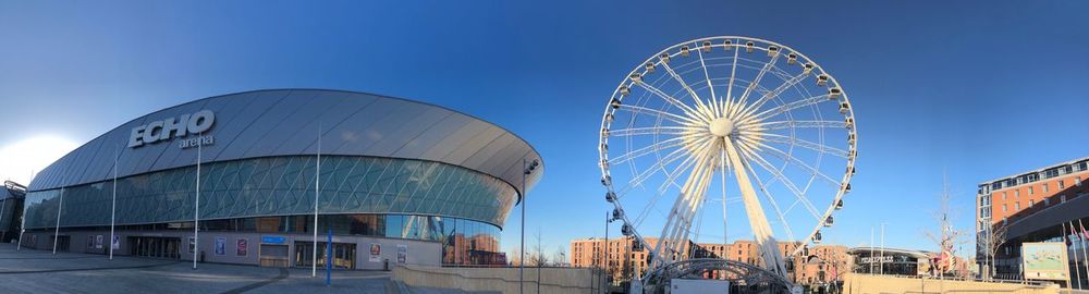 Ferris wheel in city against clear blue sky