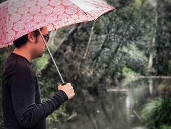 Midsection of man holding umbrella while standing in rain