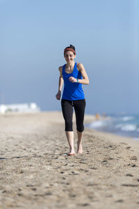 Full length of woman exercising at beach