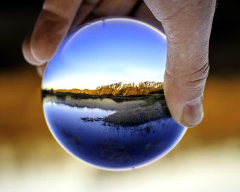 Cropped hand of person holding crystal ball with reflection