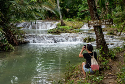Woman photographing by stream
