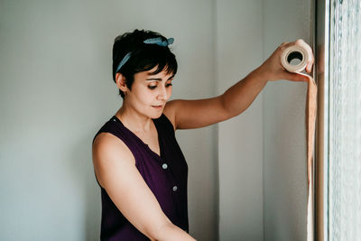 Young woman looking away while standing against door