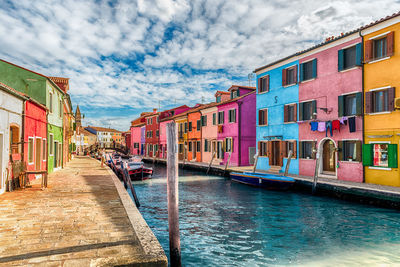 Buildings by canal against sky in city