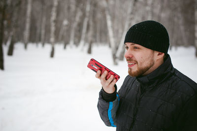 Close-up of man talking on phone while standing on snow covered field