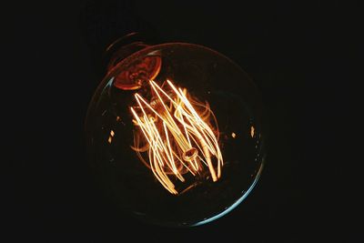 Close-up of illuminated light bulb against black background