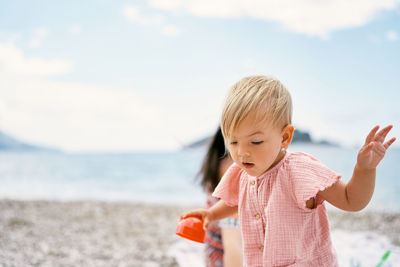 Cute girl holding toy on beach