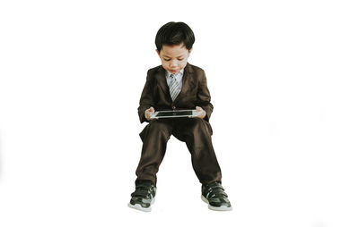 Boy using digital tablet while sitting in mid-air against white background