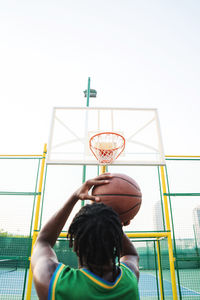 Rear view of boy holding camera against clear sky