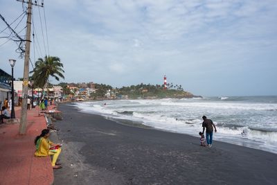 Men on beach in city against sky