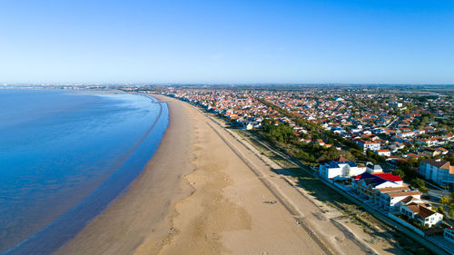 Aerial view of city by sea against clear blue sky