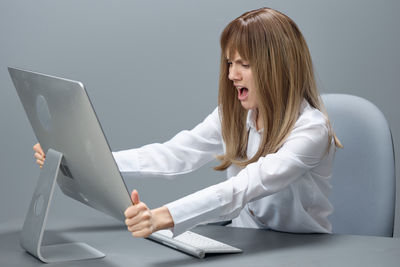 Side view of woman using laptop while sitting on bed at home