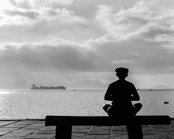 Rear view of silhouette man on sea against sky