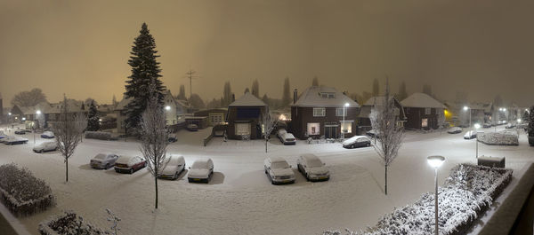 Cars on street amidst buildings against sky during winter