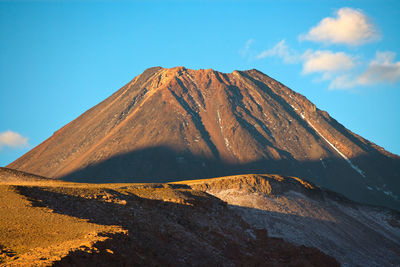 Scenic view of volcanic mountain against blue sky