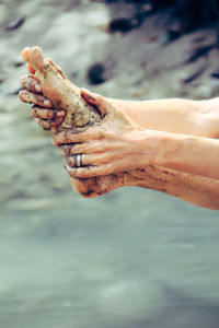 Close-up of woman holding dirty leg at beach