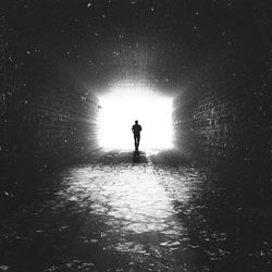 Rear view of silhouette man standing in tunnel