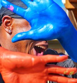 Close-up of man with colorful hands gesturing stop sign