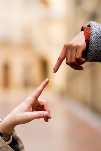 Side view of crop multiethnic stretching hands with finger in street