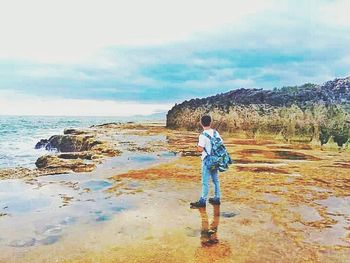 Full length of man standing in sea against sky