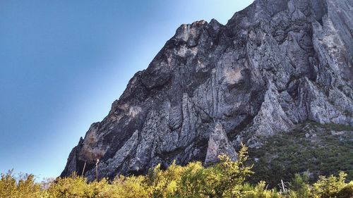 Low angle view of rocky mountains against clear blue sky