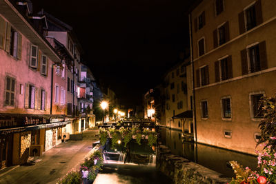 Illuminated street amidst buildings in city at night