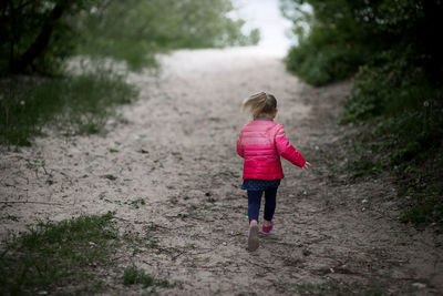 Rear view of girl walking on dirt road