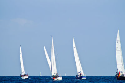 Sailboats on sea against clear blue sky