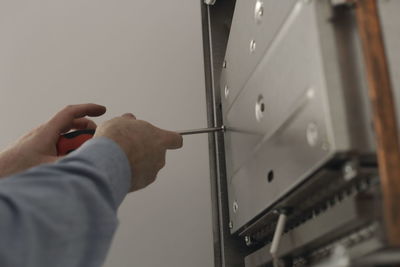 Close-up of cropped hand repairing electronic equipment at home