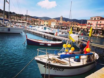 Boats moored at harbor against sky