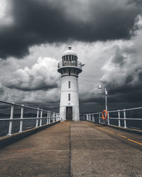 Lighthouse by building against sky